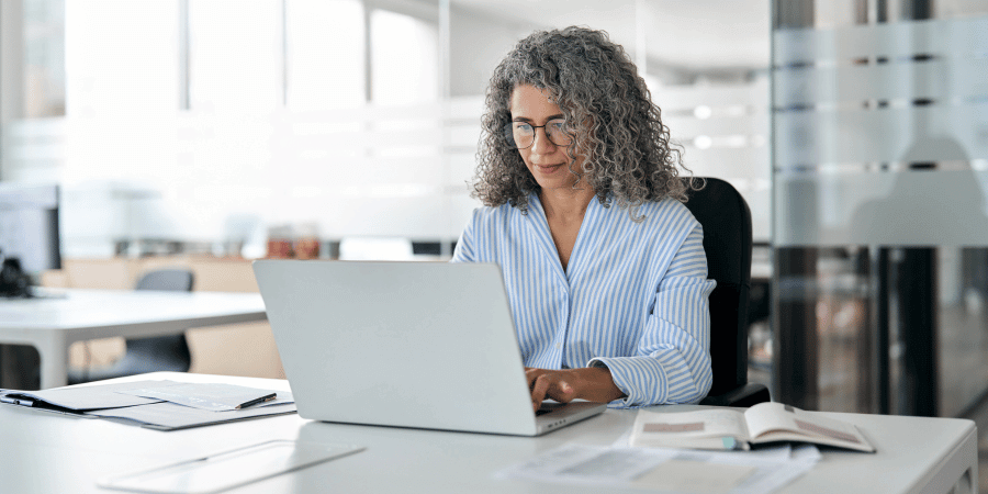 Executive leader wearing glasses looking at laptop using computer in office sitting at a desk.